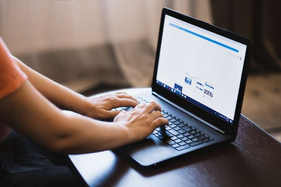 Une personne tape sur un ordinateur portable ouvert sur une page web, illustrant la recherche d'informations sur le web.